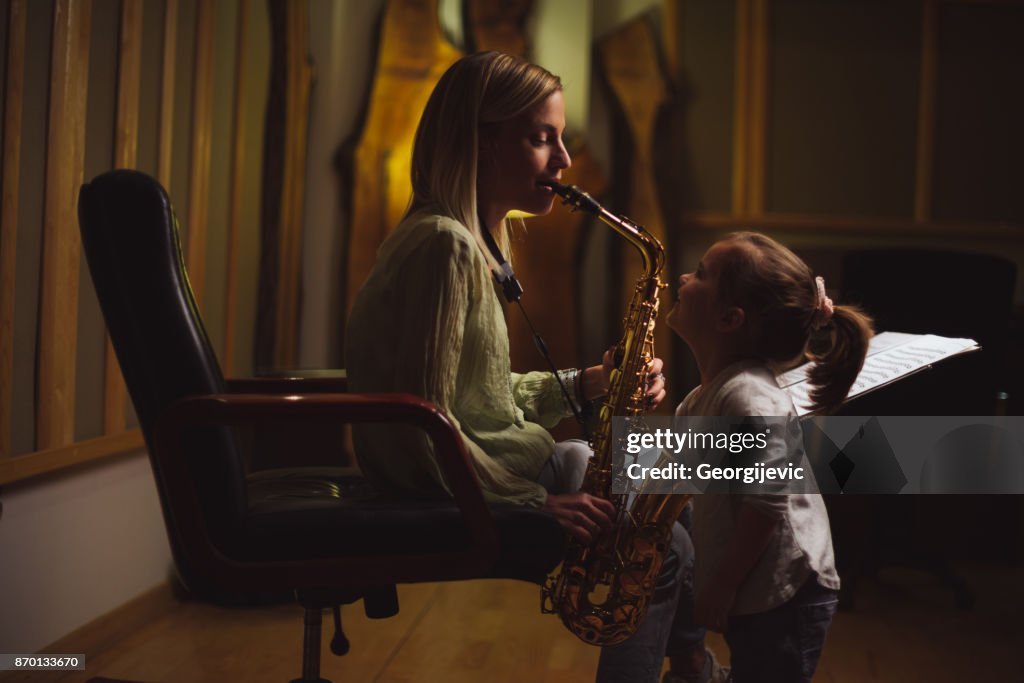 Mother playing saxophone in a music studio.
