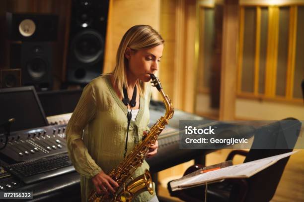 Young female musician playing saxophone in a music studio.